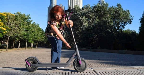 אישה מקפלת את הקורקינט החשמלי שלה